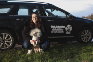 Laetitia Dupuy, fondatrice de Angel Guardian, posant devant son véhicule noir sérigraphié avec un chien.